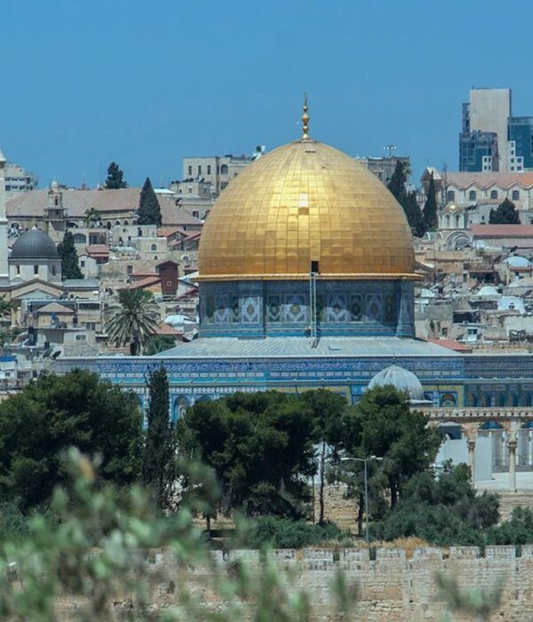 The golden Dome of the Rock rises above the stone houses and church towers of Jerusalem's Old City, seen across the city wall from the Mount of Olives.
