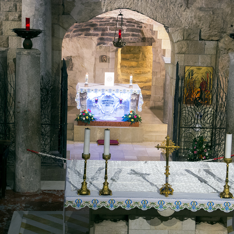 Nazareth tour: the Grotto of the Annunciation Candles and a brass cross on an altar in front of the Grotto of the Annunciation in Nazareth, a stone cave with an altar inscribed "Verbum caro hic factum est".